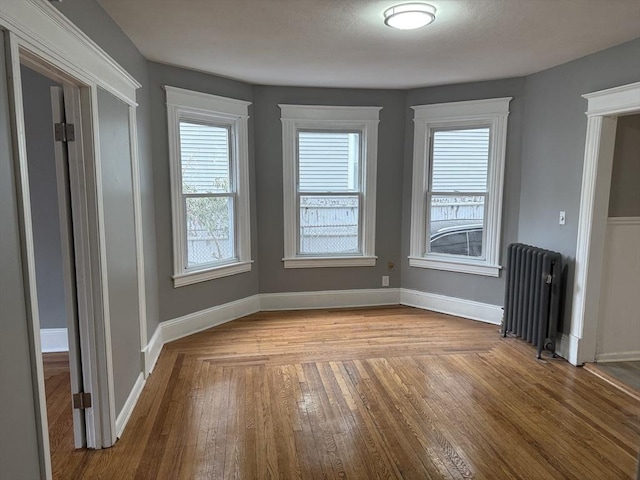 interior space featuring baseboards, hardwood / wood-style floors, and radiator heating unit