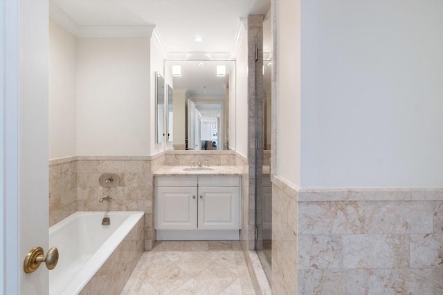 bathroom featuring crown molding, tile walls, a wainscoted wall, a bath, and vanity