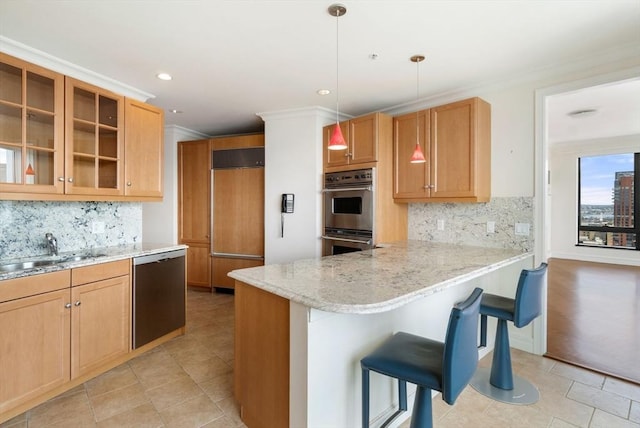 kitchen with a sink, a kitchen breakfast bar, appliances with stainless steel finishes, a peninsula, and glass insert cabinets