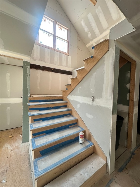 stairs with vaulted ceiling and wood-type flooring