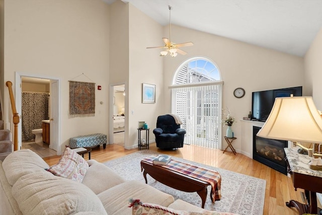 905 Village Ln Unit 905, Bellingham, MA 02019 - living room with high vaulted ceiling, ceiling fan, a glass covered fireplace, light wood finished floors, and stairway
