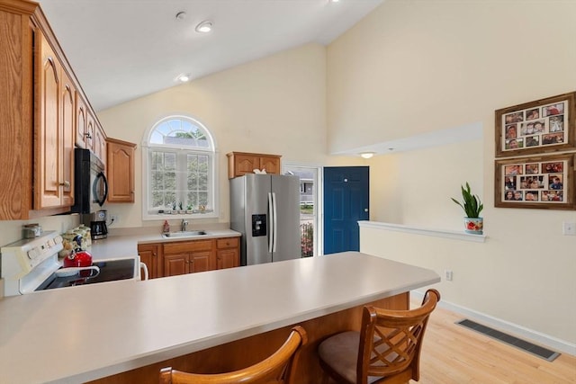 905 Village Ln Unit 905, Bellingham, MA 02019 - kitchen featuring stainless steel fridge with ice dispenser, white electric stove, vaulted ceiling, a peninsula, and light countertops