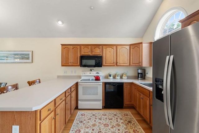 905 Village Ln Unit 905, Bellingham, MA 02019 - kitchen featuring black appliances, a peninsula, light wood-type flooring, light countertops, and vaulted ceiling