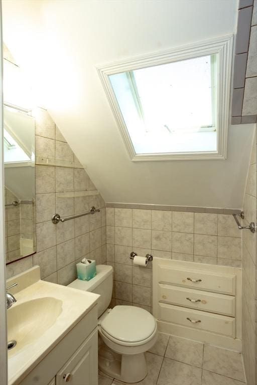 5 Clement Ave, Peabody, MA 01960 - bathroom featuring tile walls, vanity, toilet, tile patterned flooring, and a skylight