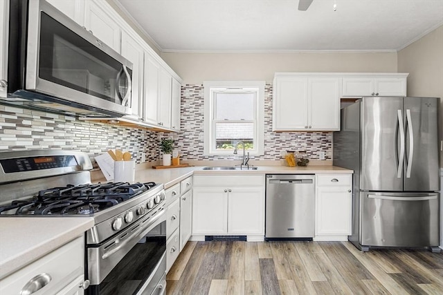 24 Willard St, Malden, MA 02148 - kitchen featuring appliances with stainless steel finishes, crown molding, white cabinetry, decorative backsplash, and light countertops