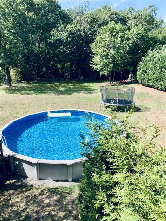 view of swimming pool featuring a trampoline and a yard
