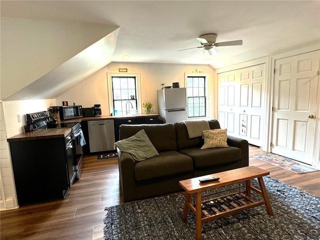 living area with dark wood-style floors, vaulted ceiling, and a ceiling fan