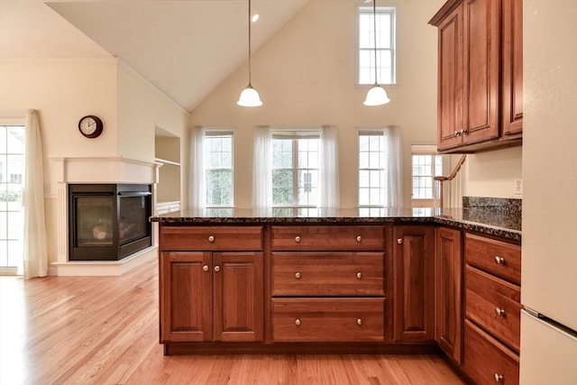 12 Braeburn Ln Unit 12, Ashland, MA 01721 - kitchen featuring a towering ceiling, brown cabinets, a peninsula, light wood-style flooring, and dark stone countertops