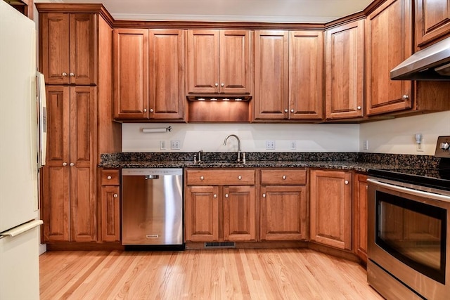 12 Braeburn Ln Unit 12, Ashland, MA 01721 - kitchen featuring appliances with stainless steel finishes, under cabinet range hood, light wood-style floors, brown cabinets, and dark stone countertops