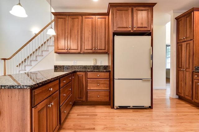 12 Braeburn Ln Unit 12, Ashland, MA 01721 - kitchen featuring freestanding refrigerator, brown cabinets, light wood-style floors, a peninsula, and ornamental molding