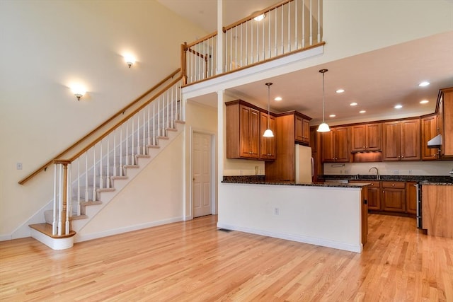 12 Braeburn Ln Unit 12, Ashland, MA 01721 - kitchen with white fridge, light wood finished floors, brown cabinetry, a peninsula, and a towering ceiling