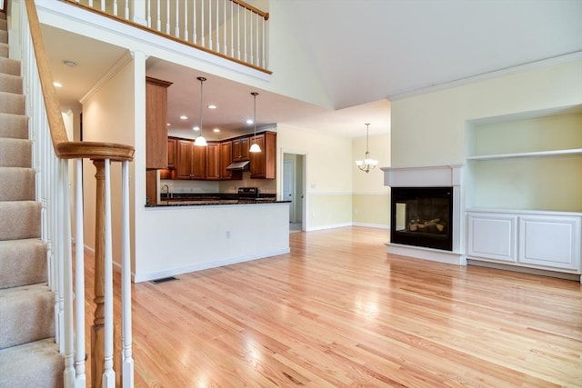 12 Braeburn Ln Unit 12, Ashland, MA 01721 - unfurnished living room with light wood-type flooring, ornamental molding, stairs, a multi sided fireplace, and high vaulted ceiling