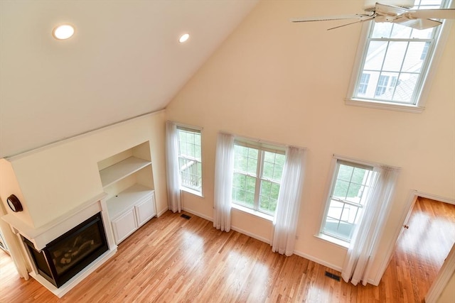 12 Braeburn Ln Unit 12, Ashland, MA 01721 - unfurnished living room with high vaulted ceiling, a glass covered fireplace, light wood-style flooring, recessed lighting, and built in shelves