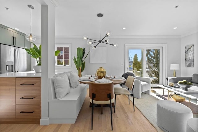 dining area with an inviting chandelier, ornamental molding, and light hardwood / wood-style floors