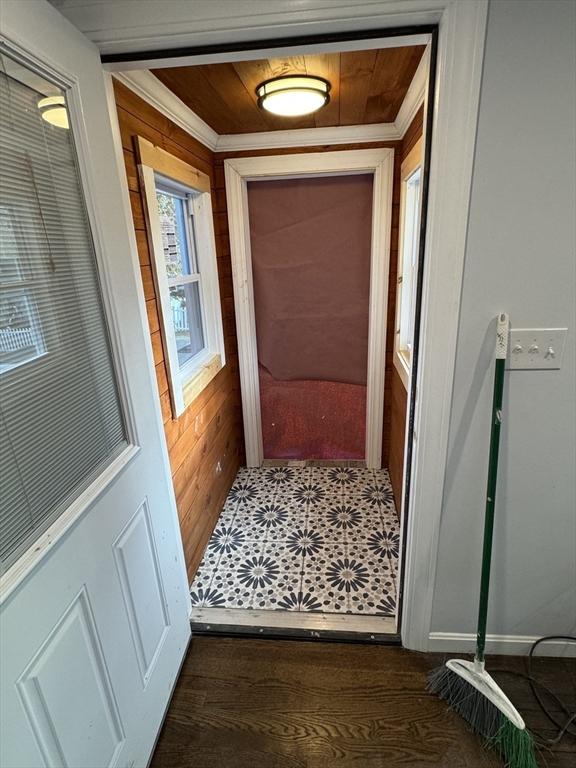 doorway to outside featuring wooden walls, wooden ceiling, dark hardwood / wood-style floors, and ornamental molding