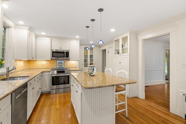 8 Warren Rd, Marblehead, MA 01945 - kitchen with appliances with stainless steel finishes, a sink, light wood-type flooring, decorative backsplash, and a kitchen breakfast bar