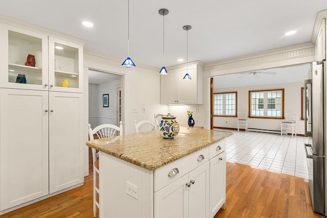8 Warren Rd, Marblehead, MA 01945 - kitchen featuring freestanding refrigerator, ornamental molding, light stone counters, baseboard heating, and a center island