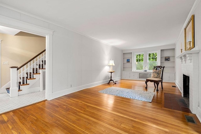 8 Warren Rd, Marblehead, MA 01945 - sitting room featuring hardwood / wood-style flooring, a fireplace, stairs, built in shelves, and baseboards