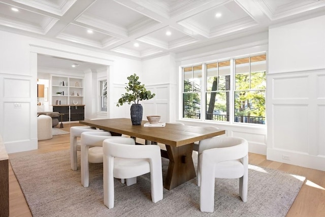 dining space with beam ceiling, built in shelves, coffered ceiling, light hardwood / wood-style flooring, and ornamental molding