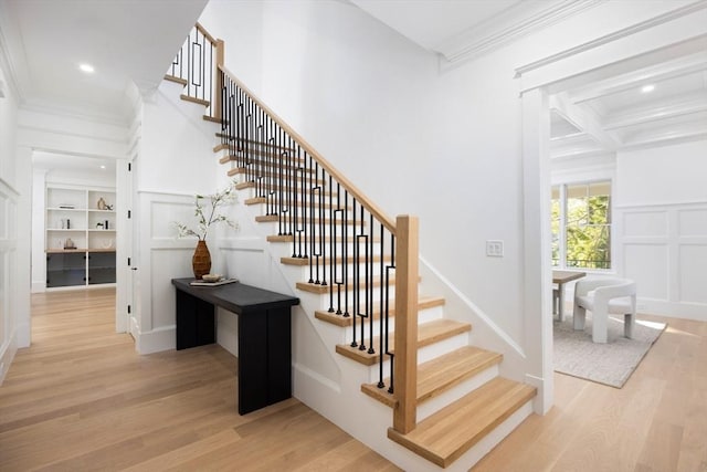 staircase featuring wood-type flooring, coffered ceiling, and ornamental molding