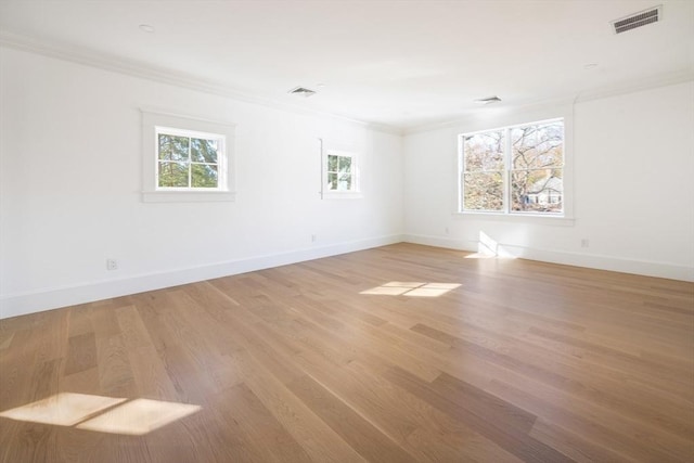 spare room featuring wood-type flooring, ornamental molding, and a healthy amount of sunlight