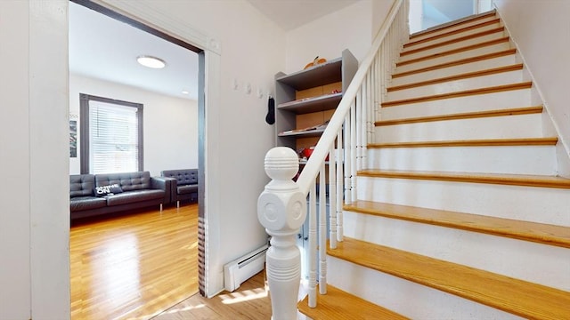 stairway with hardwood / wood-style flooring and a baseboard heating unit