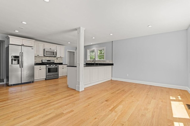 328 N Main St, Sharon, MA 02067 - kitchen with stainless steel appliances, dark countertops, decorative backsplash, light wood-style flooring, and recessed lighting