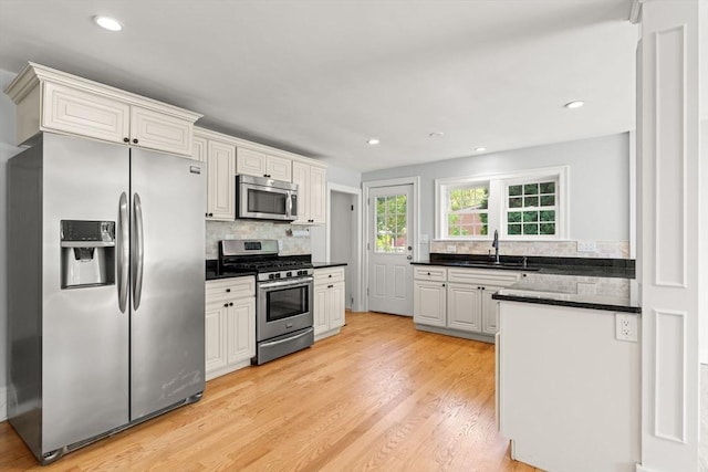 328 N Main St, Sharon, MA 02067 - kitchen featuring appliances with stainless steel finishes, dark countertops, light wood-type flooring, decorative backsplash, and recessed lighting