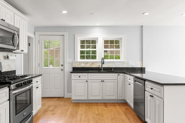 328 N Main St, Sharon, MA 02067 - kitchen featuring appliances with stainless steel finishes, tasteful backsplash, light wood-style floors, white cabinets, and a peninsula
