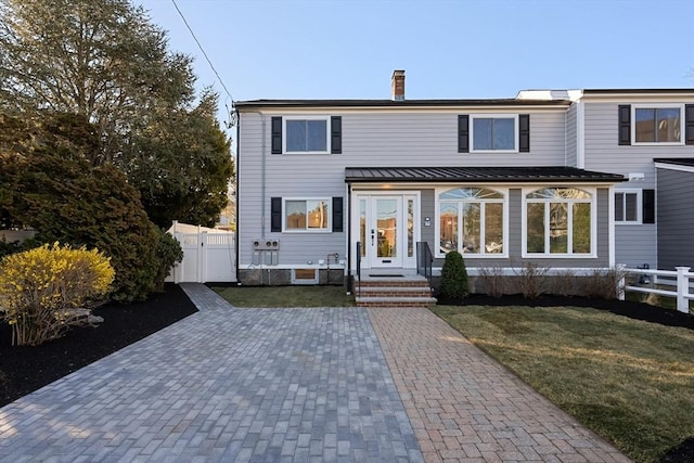 rear view of property with a yard, fence, and a gate