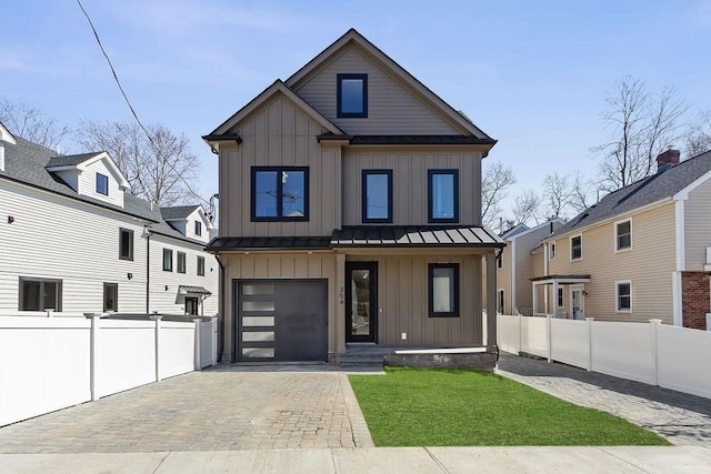 view of front of home featuring board and batten siding, decorative driveway, a standing seam roof, and fence