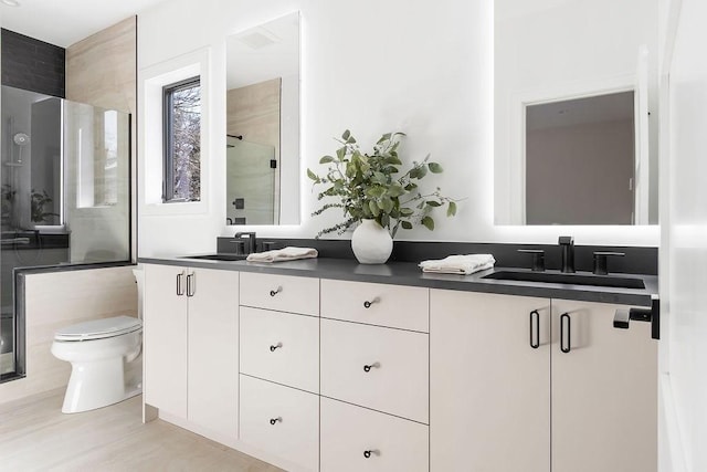 full bathroom with a sink, toilet, double vanity, and a shower stall