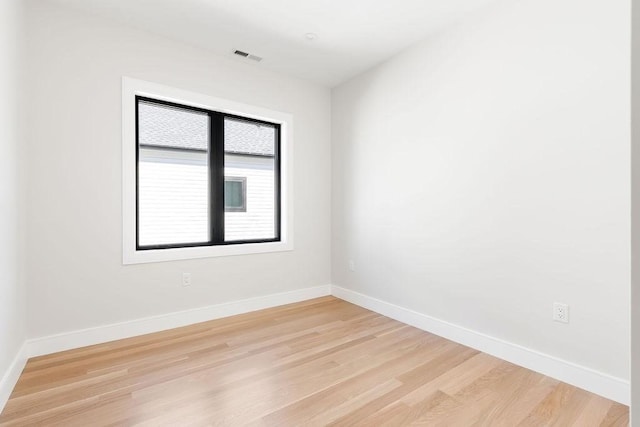 empty room featuring light wood finished floors, visible vents, and baseboards