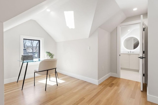 office area with a sink, baseboards, lofted ceiling, and light wood-style flooring