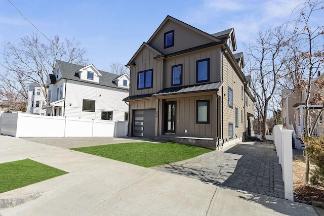 view of front of house with concrete driveway, board and batten siding, an attached garage, and fence