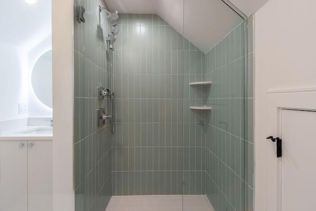 bathroom with vanity, lofted ceiling, and a tile shower