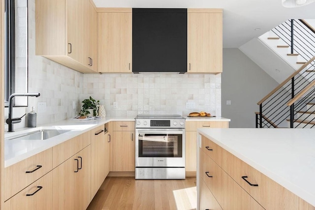 kitchen featuring a sink, stainless steel range with electric cooktop, light wood finished floors, and light brown cabinetry