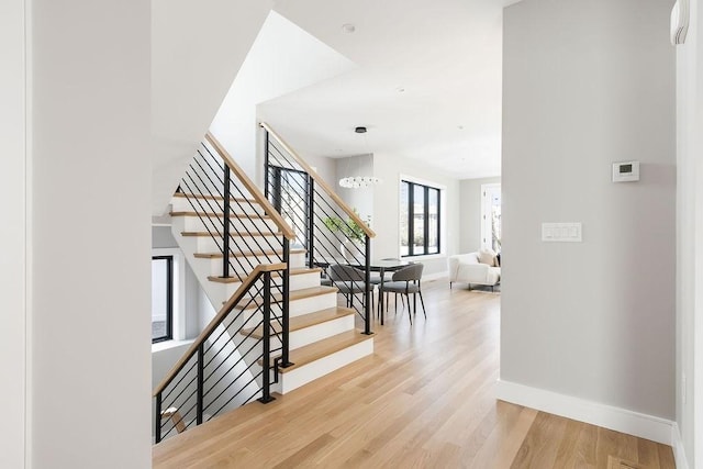 staircase with a chandelier, baseboards, and wood finished floors