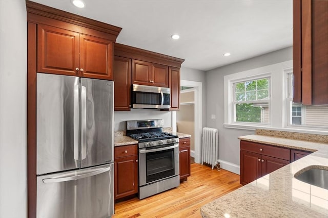 30 Gilbert Rd Unit 30, Belmont, MA 02478 - kitchen featuring appliances with stainless steel finishes, radiator heating unit, light wood finished floors, light stone countertops, and recessed lighting