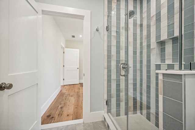 bathroom with a shower with door and wood-type flooring