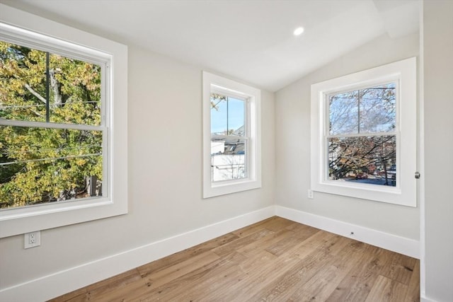 empty room featuring vaulted ceiling and light hardwood / wood-style flooring