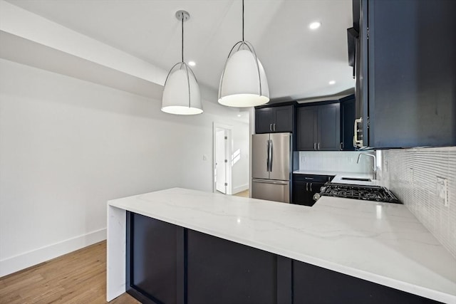 kitchen featuring stainless steel refrigerator, decorative light fixtures, tasteful backsplash, light stone counters, and kitchen peninsula