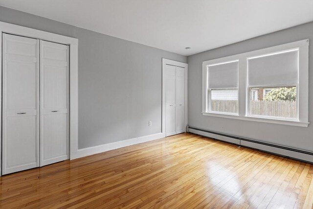 17-19 Maple St, Newton, MA 02466 - unfurnished bedroom featuring two closets, light wood-type flooring, baseboard heating, and baseboards