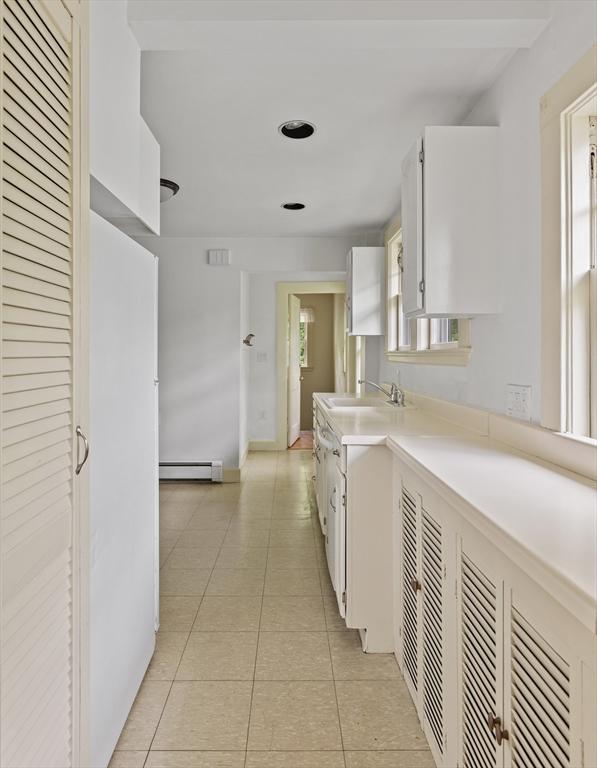 17-19 Maple St, Newton, MA 02466 - kitchen featuring a baseboard radiator, a sink, white cabinets, light tile patterned flooring, and light countertops