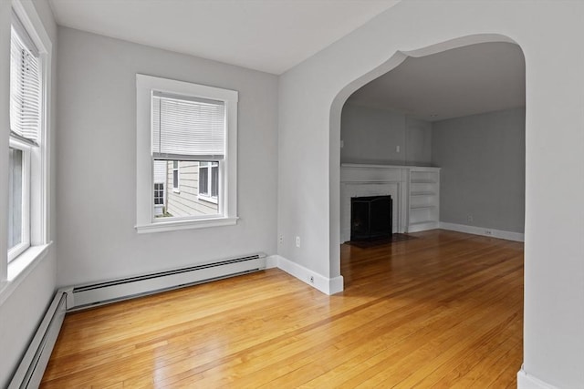 17-19 Maple St, Newton, MA 02466 - unfurnished living room featuring arched walkways, a baseboard radiator, and light wood-style floors