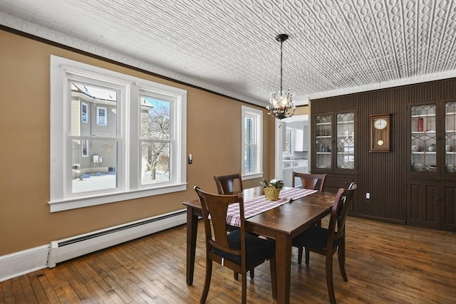 dining room with a baseboard radiator, wood-type flooring, ornamental molding, and a notable chandelier