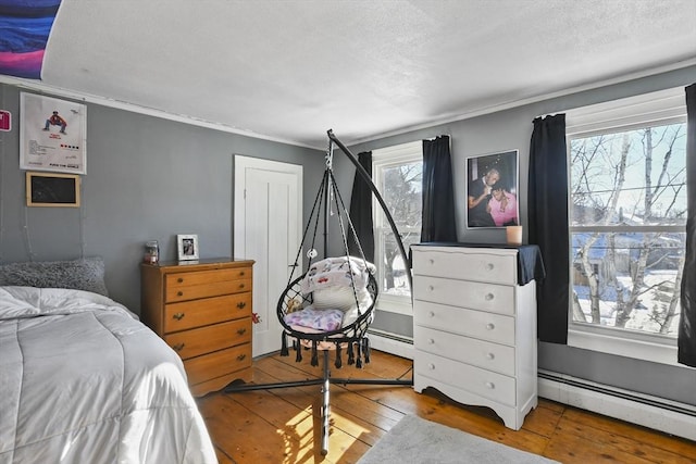 bedroom with a baseboard radiator and hardwood / wood-style floors