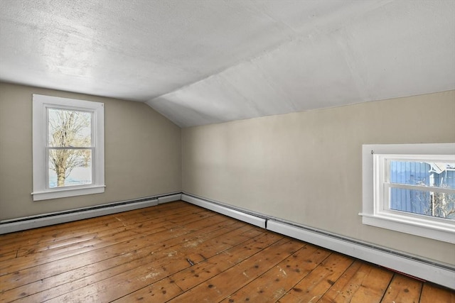 bonus room featuring lofted ceiling, a baseboard heating unit, hardwood / wood-style floors, and a textured ceiling