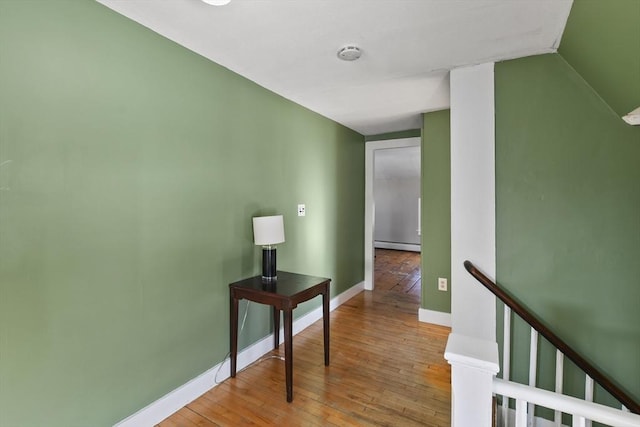 hall with light hardwood / wood-style flooring and a baseboard heating unit