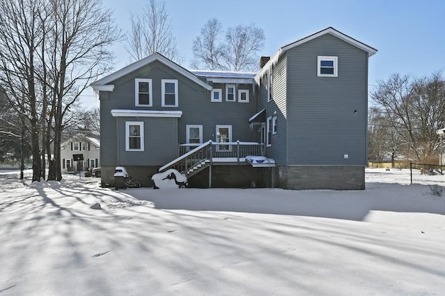 snow covered back of property featuring a deck